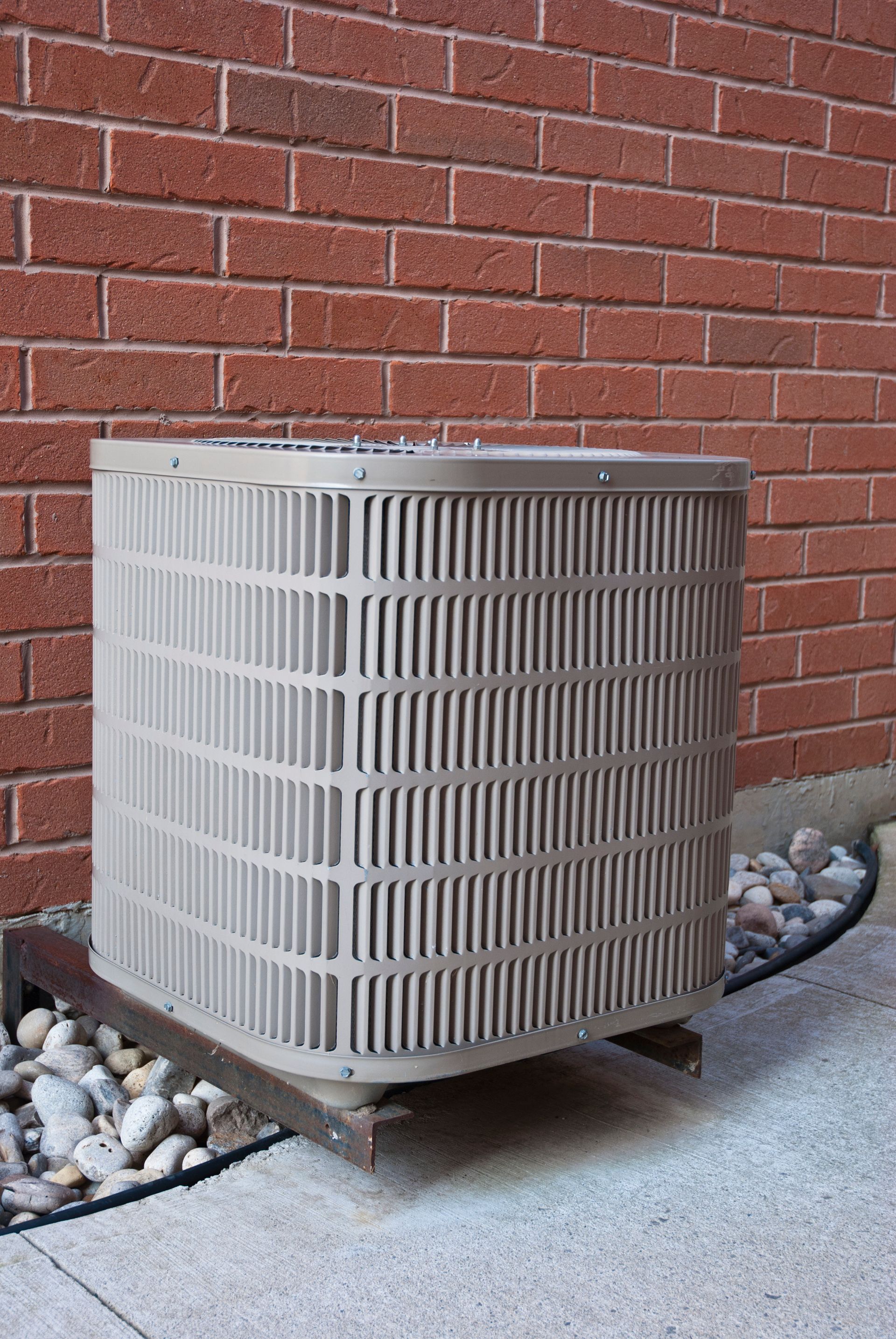 An air conditioner is sitting outside of a brick building.