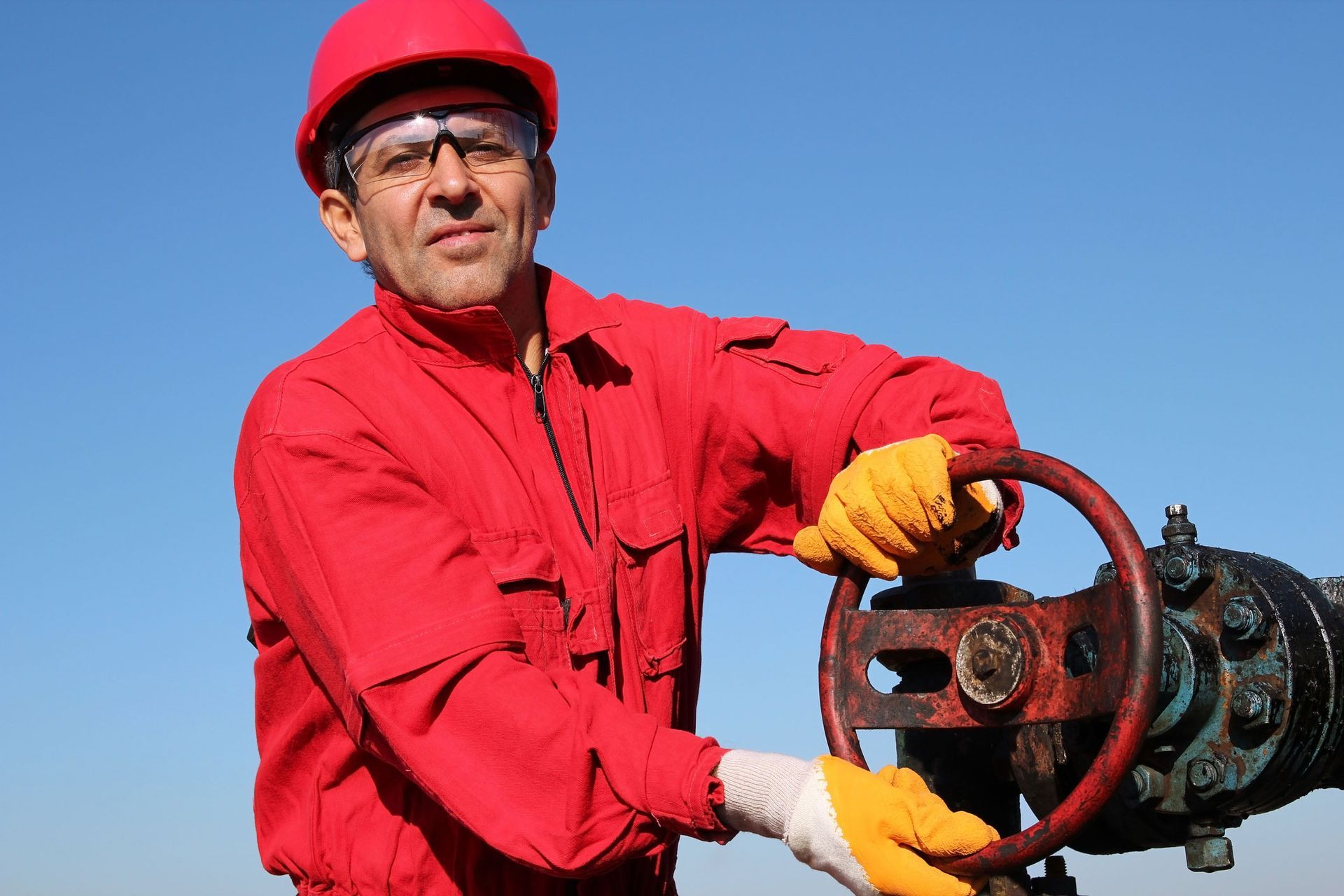 A man in a red hard hat and overalls is holding a steering wheel.