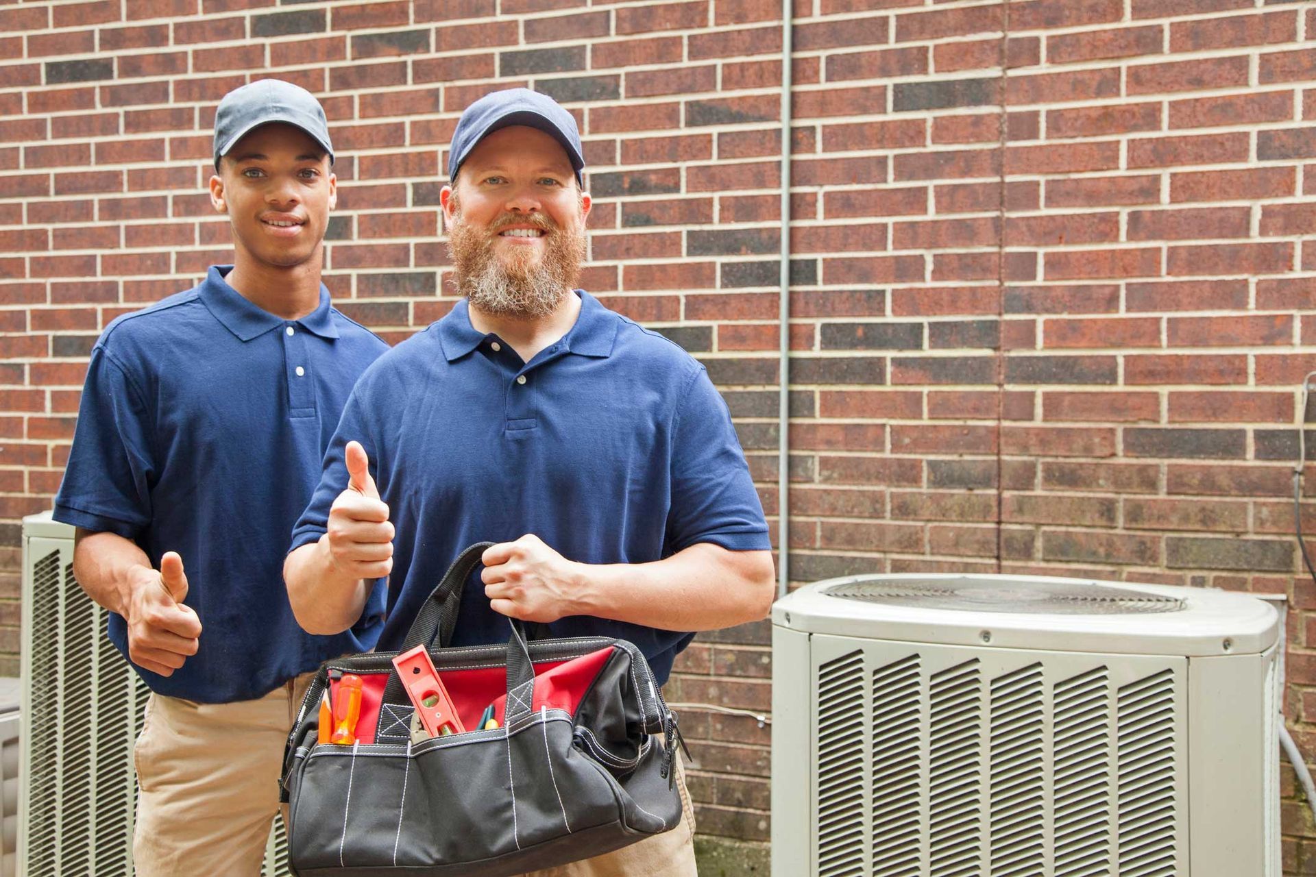 Two men are standing next to each other and giving a thumbs up.
