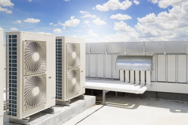 There are two air conditioners on the roof of a building.