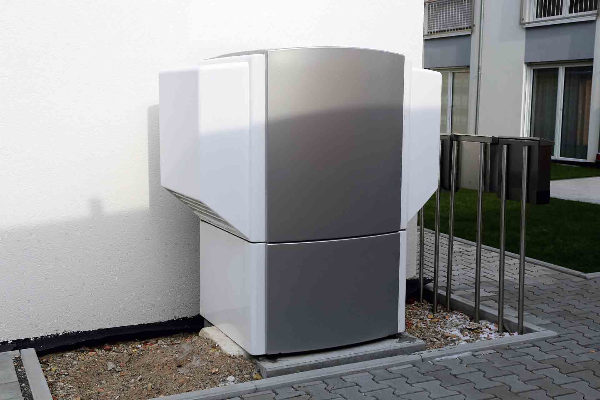 A large gray and white appliance is sitting on the side of a building.