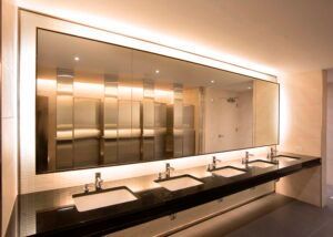 A bathroom with a row of sinks and a large mirror.