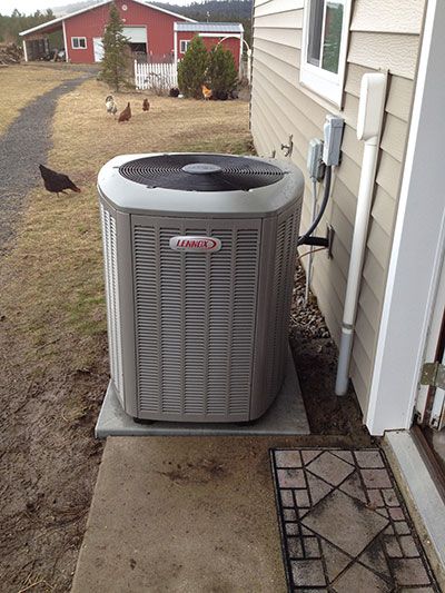 A large air conditioner is sitting on the side of a house.