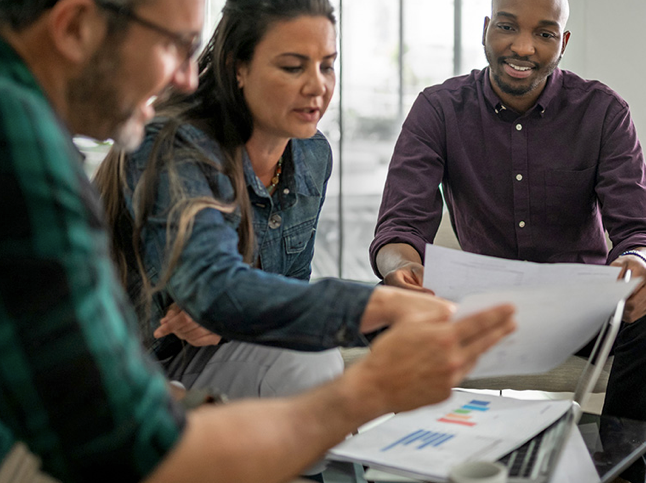 A group of people are sitting around a table looking at papers.