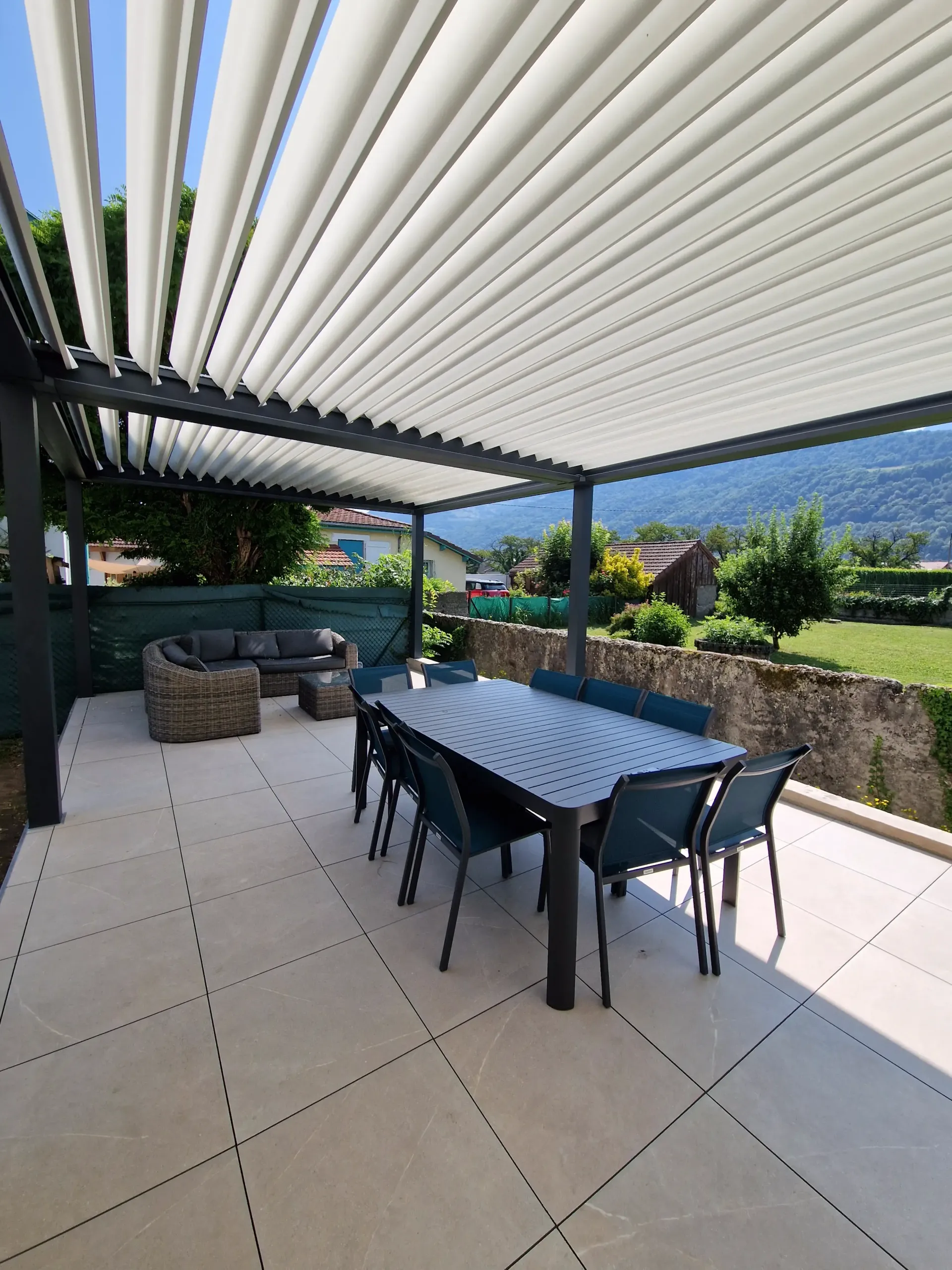 une terrasse avec une table et des chaises sous une pergola .