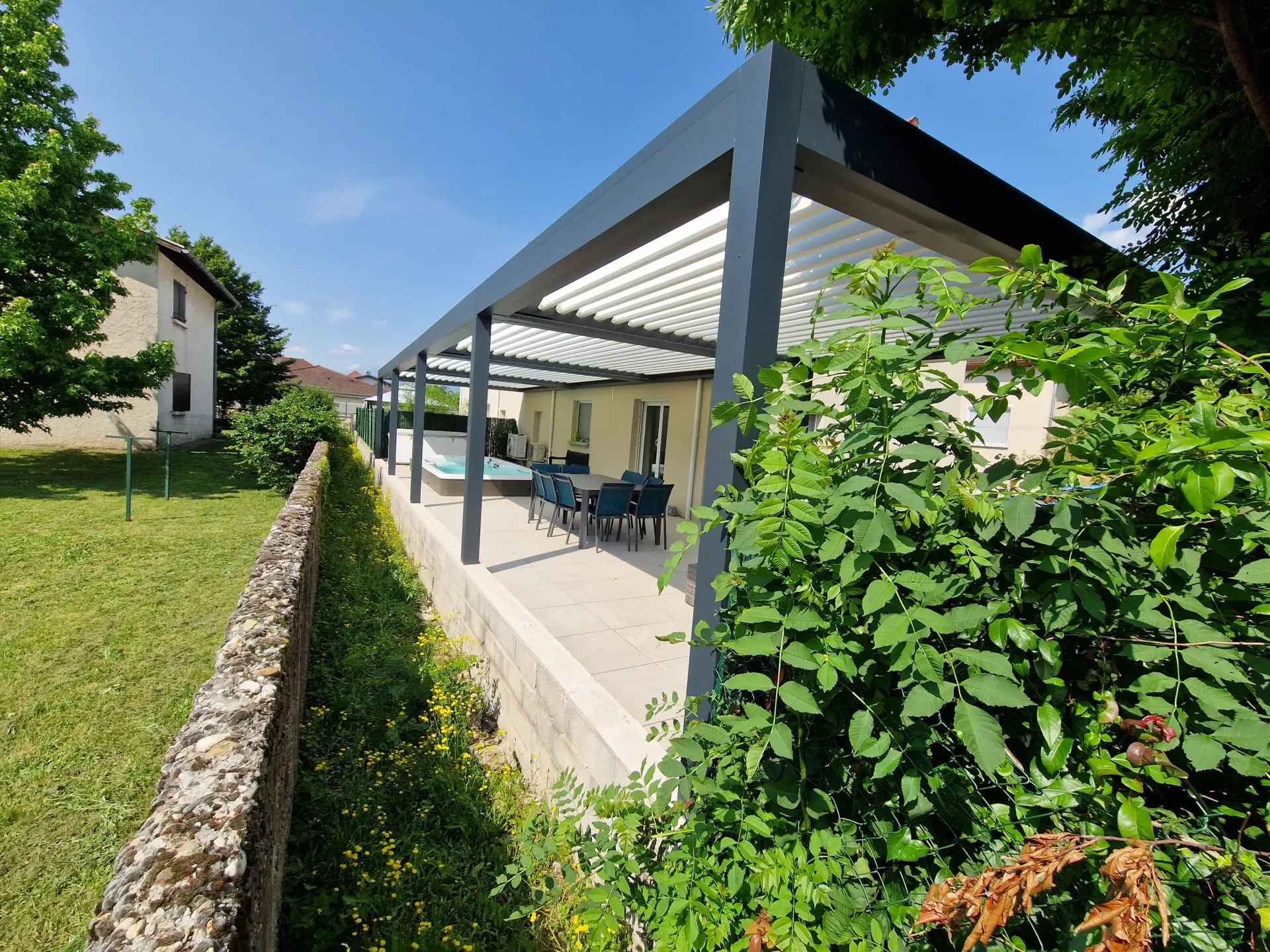 une terrasse couverte avec une table et des chaises à côté d' une maison .