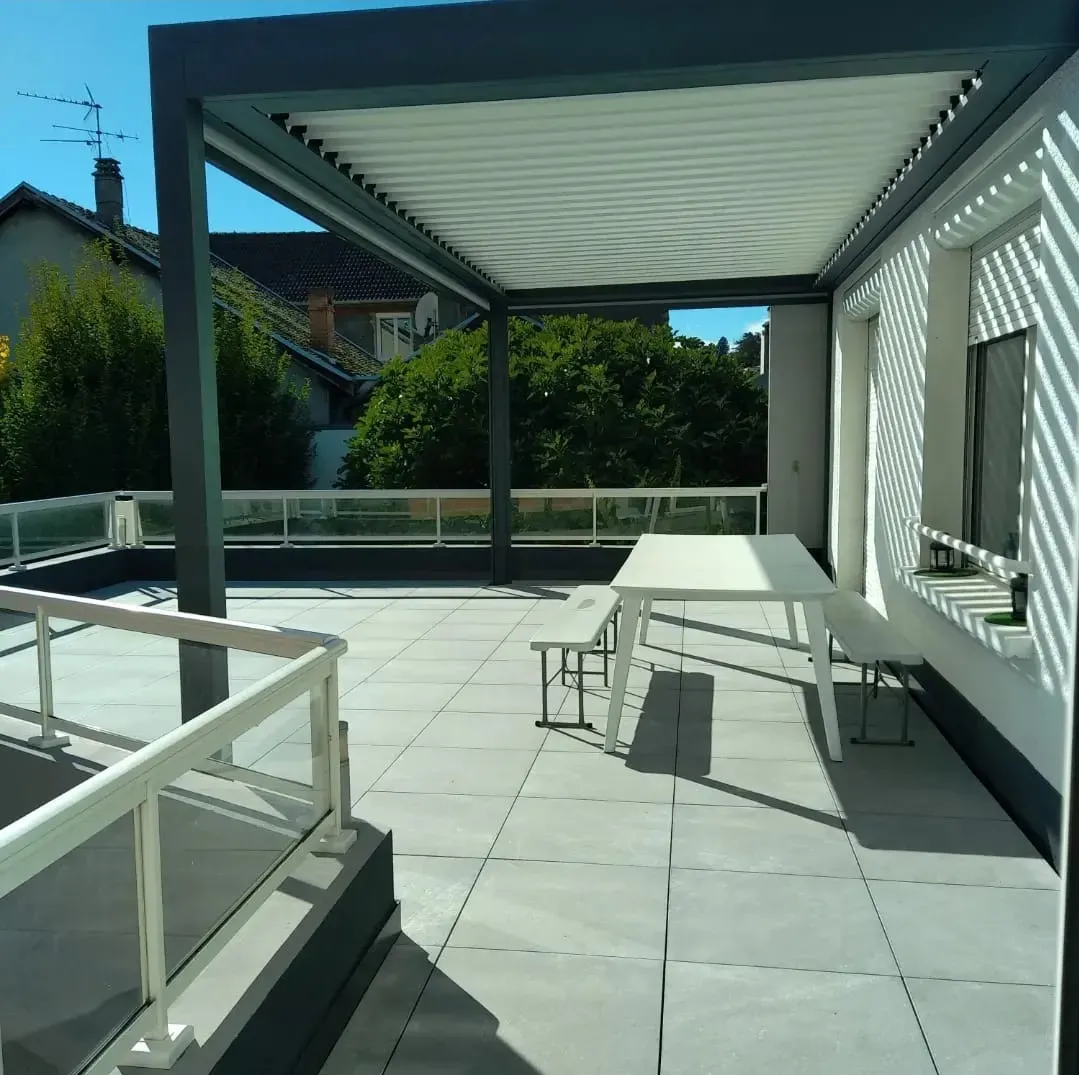 un balcon avec une table et des chaises sous une pergola