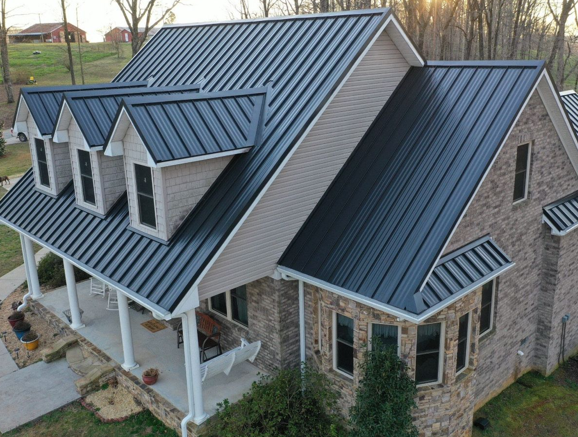 House with black metal roof and brick facade.