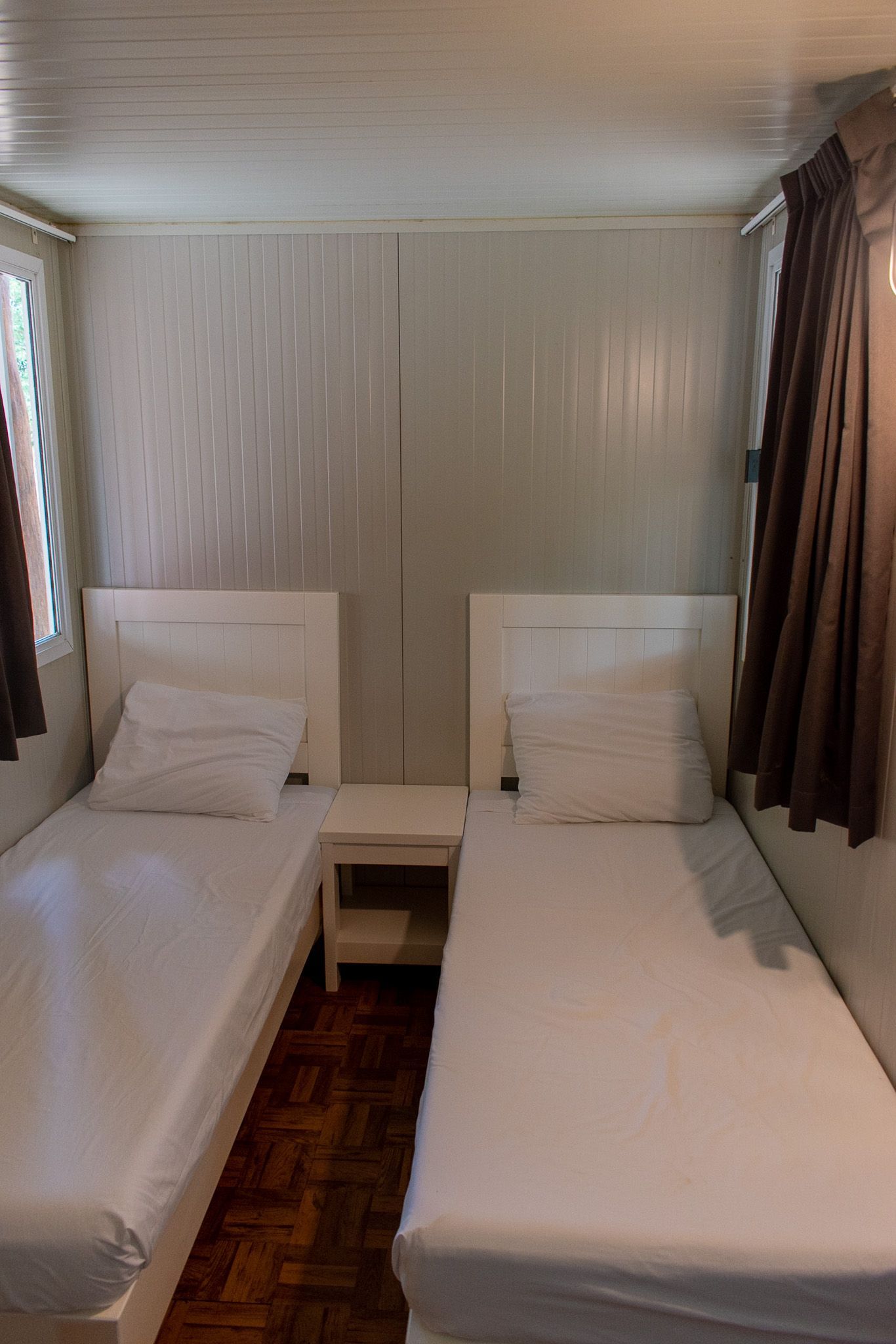 Un dormitorio con dos camas, una mesita de noche y una ventana.