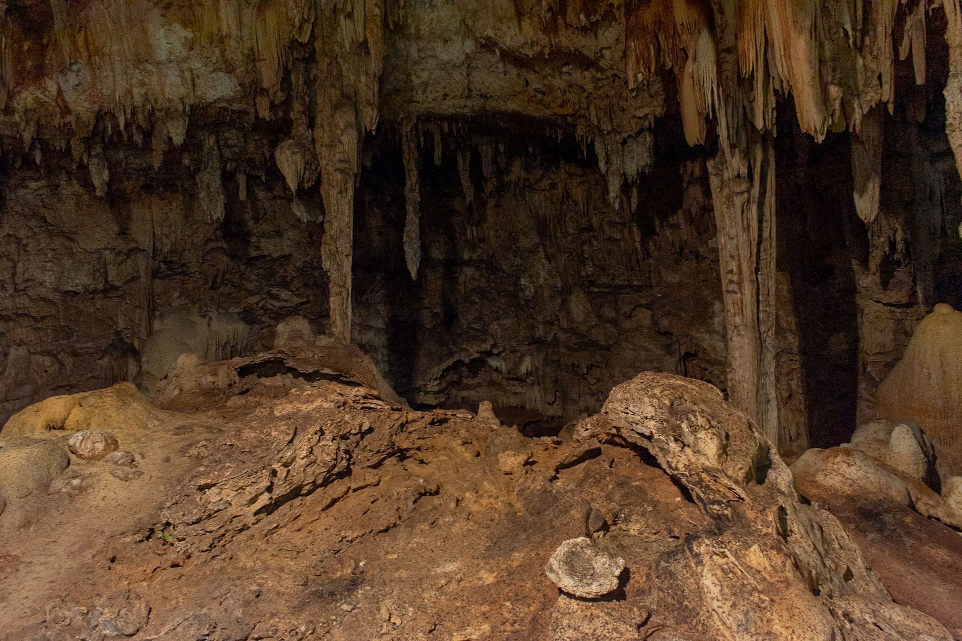 Un cenote con muchas rocas y carámbanos colgando del techo.
