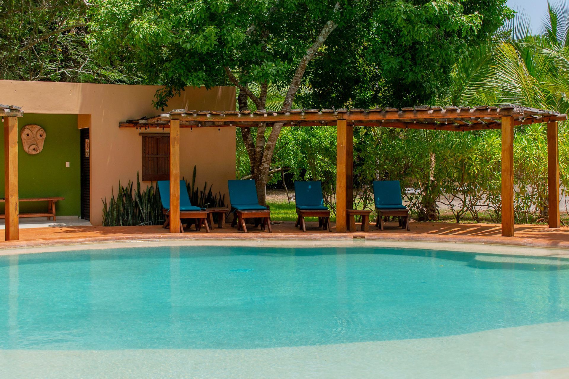 Una piscina con pérgola y sillas alrededor.