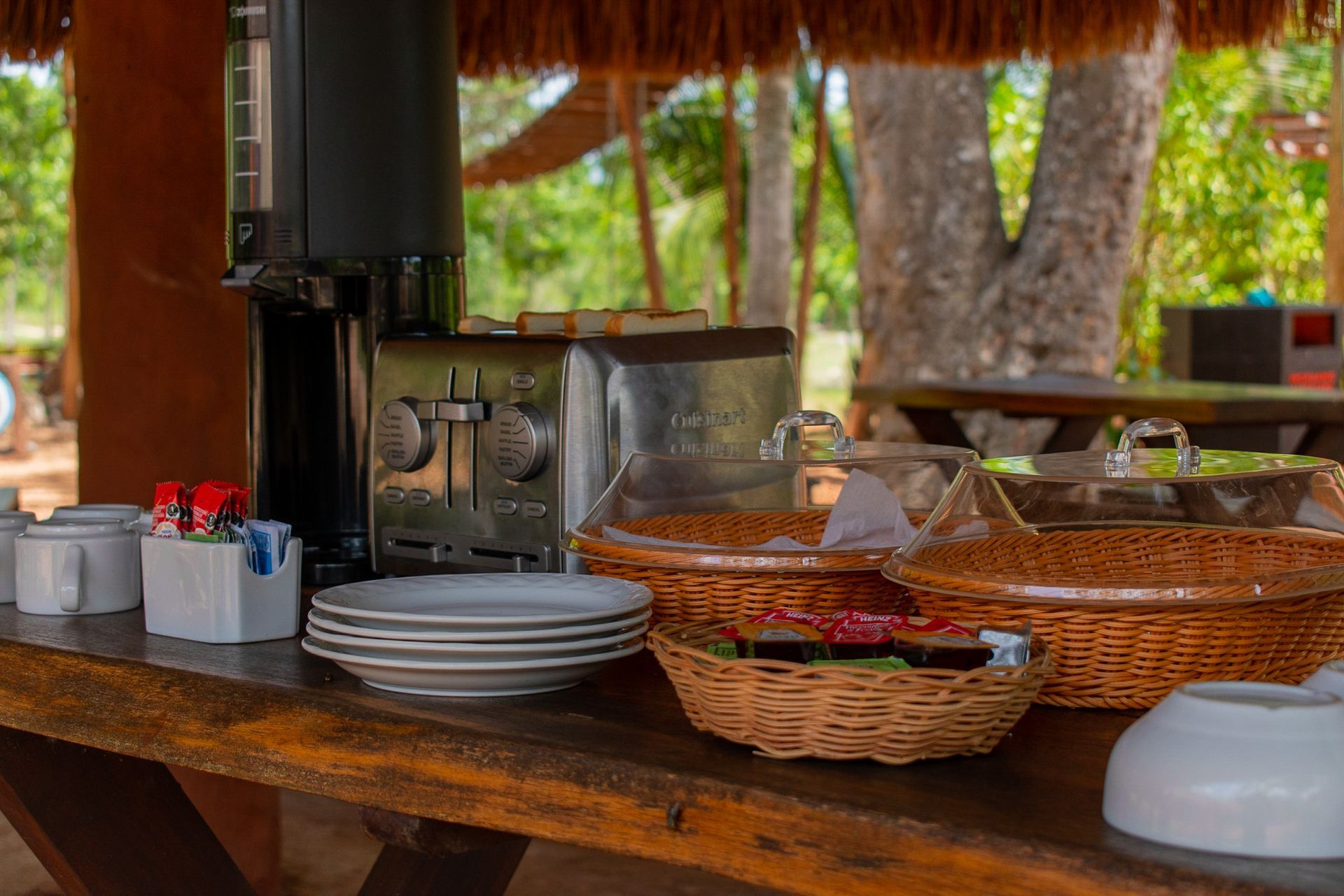 Una mesa de madera cubierta con platos, cuencos y un horno tostador.