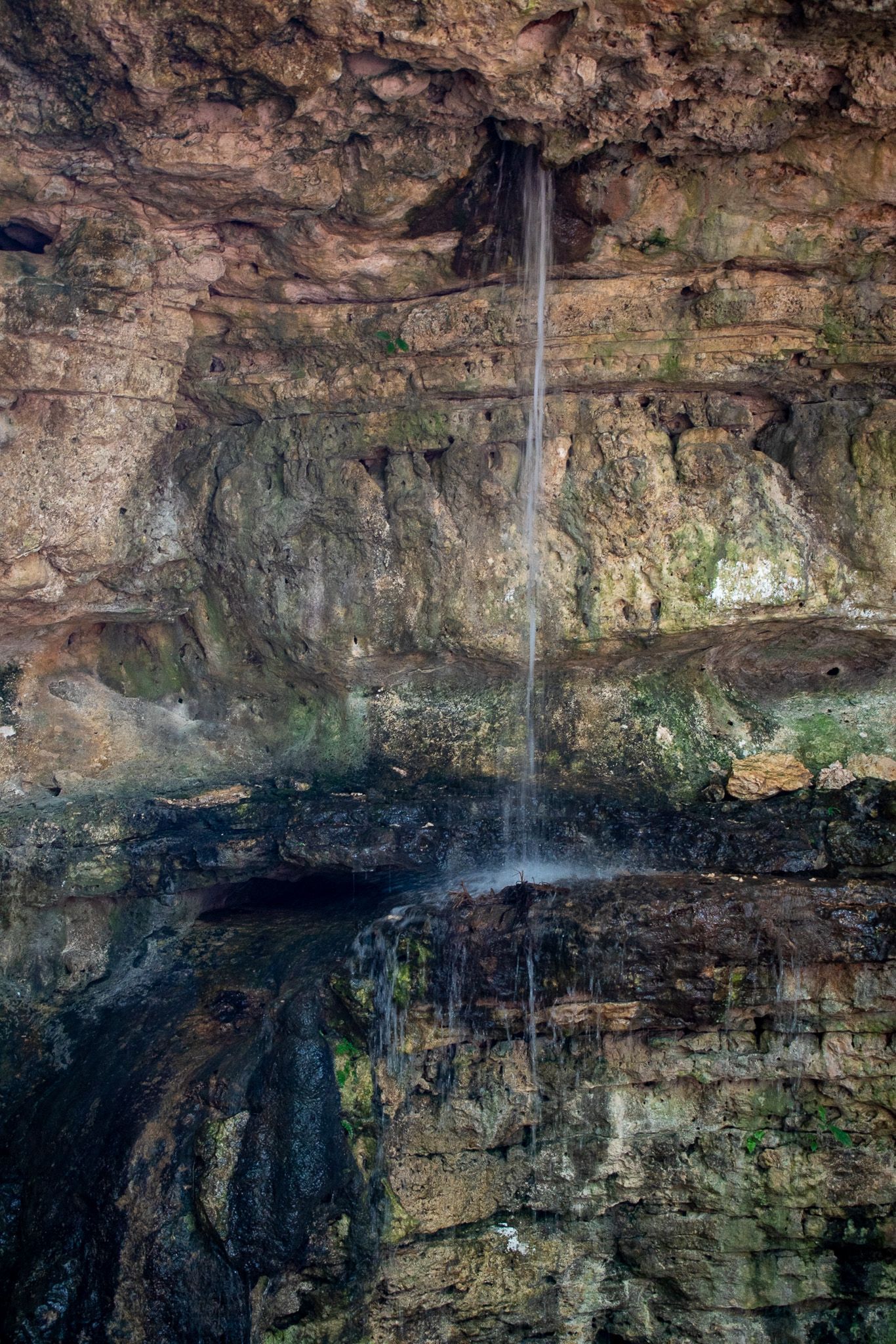 Una cascada baja por una pared de roca en una cueva.