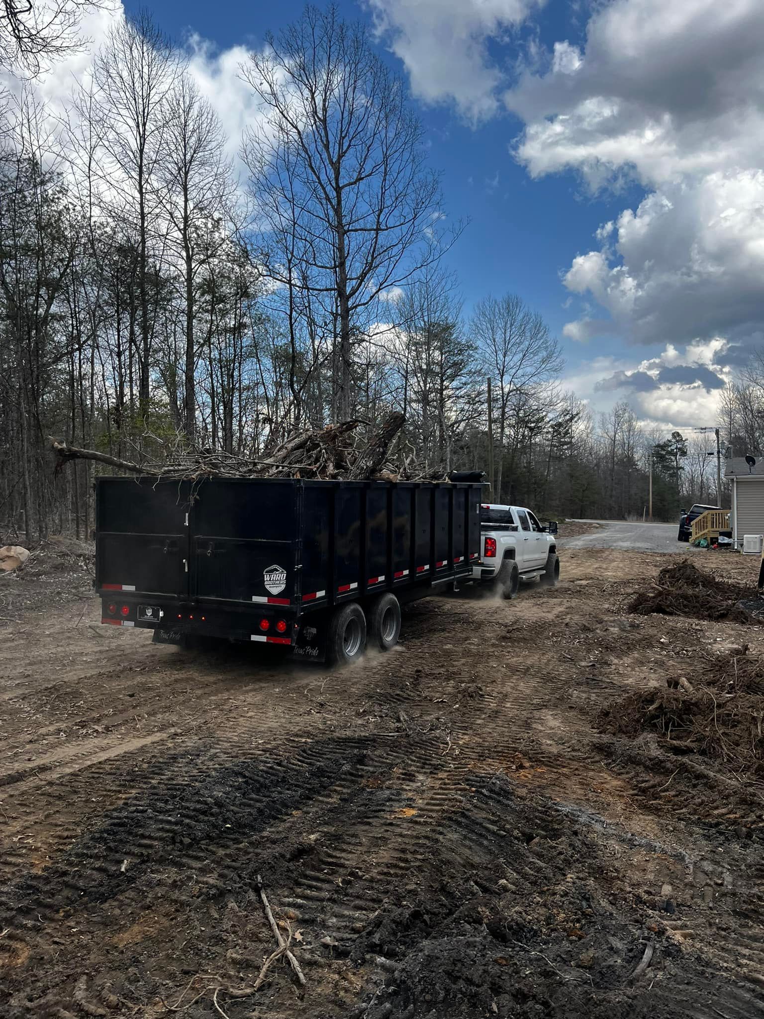 A dump truck is driving down a dirt road next to a truck.