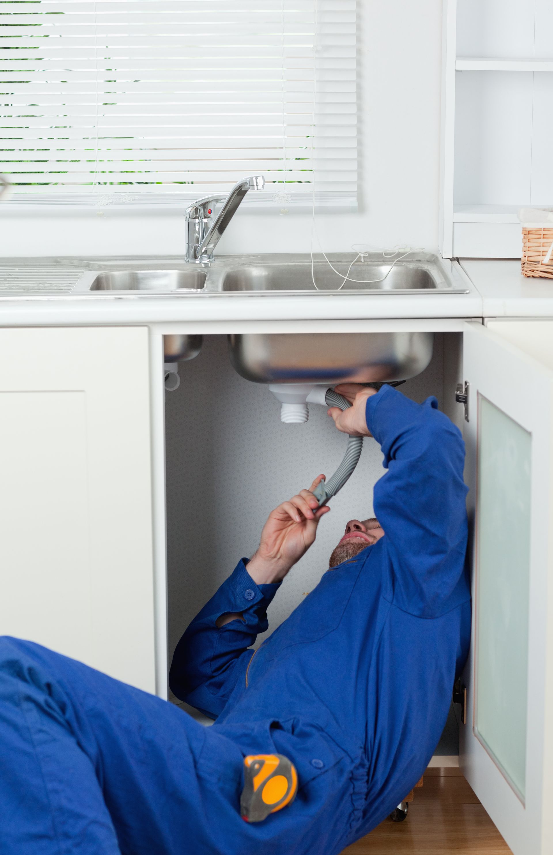 A person in blue working under a sink for D&S Plumbing - Plumbing Contractors Mcdonough Ga