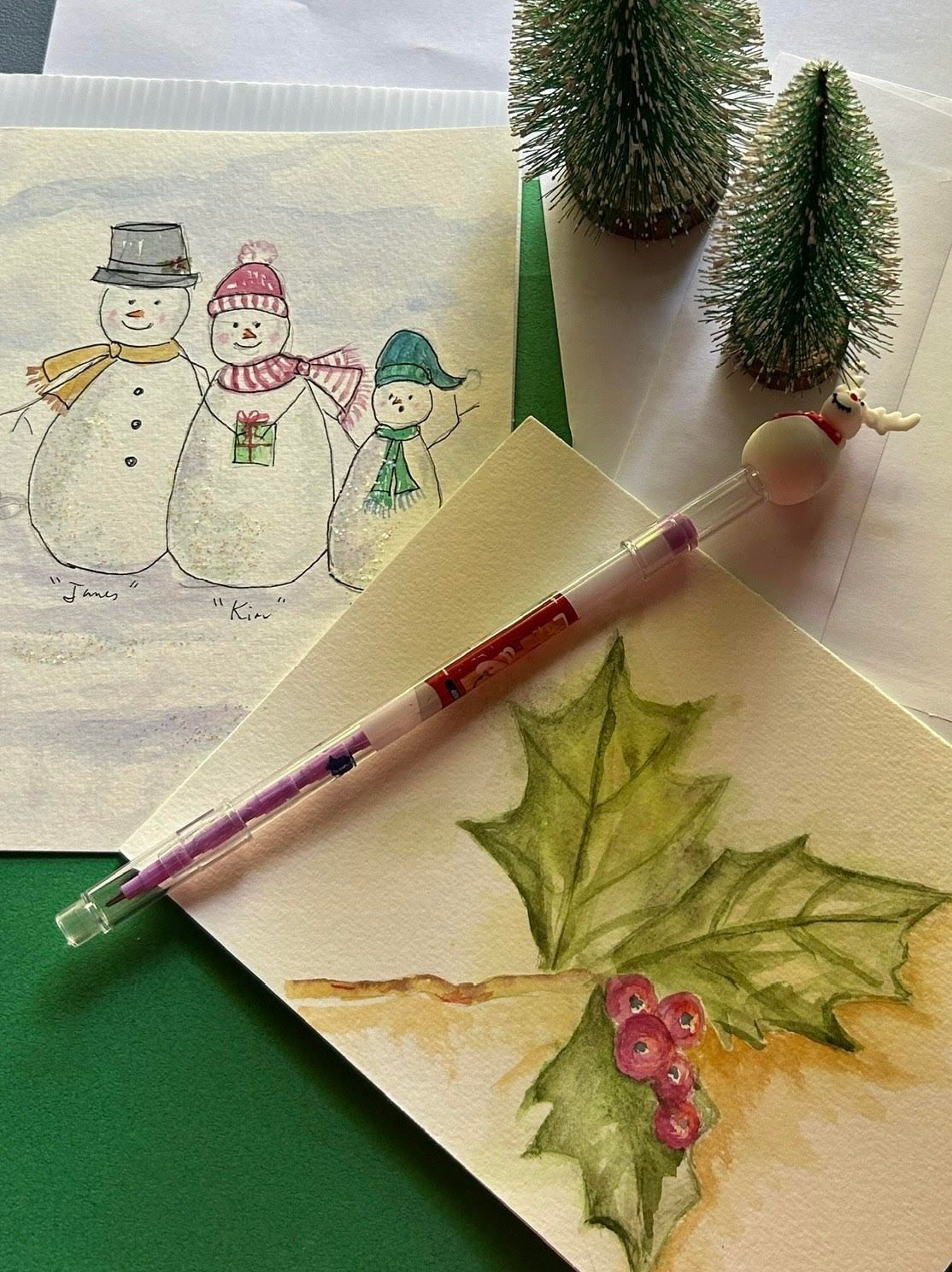 A pen with a snowman on it sits on a christmas card