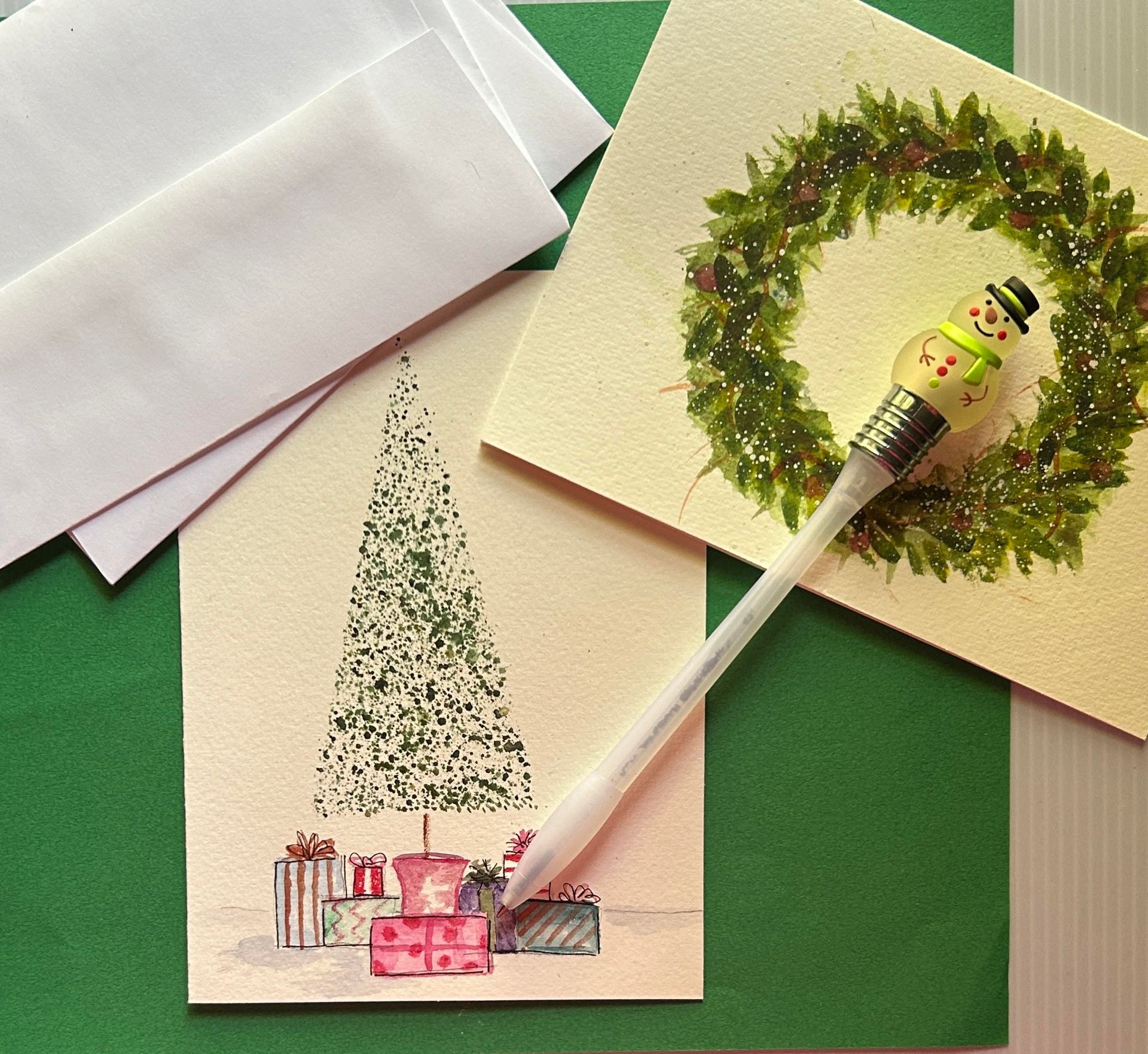 A pen is sitting on top of a painting of snowmen and holly.