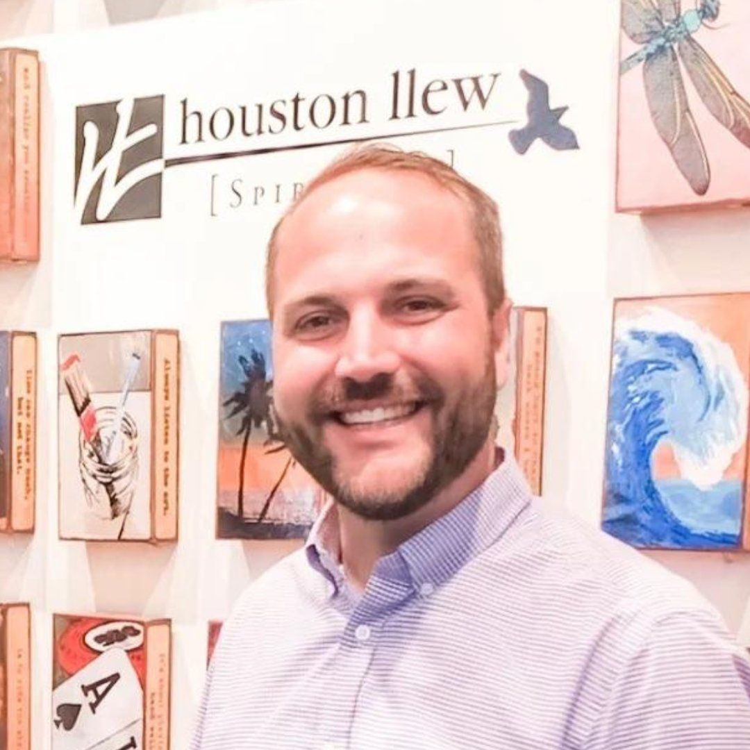 A man with a beard is smiling in front of a houston llew sign