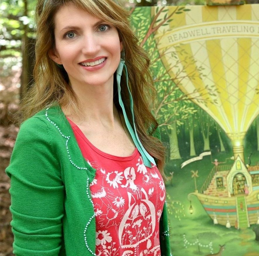 A woman stands in front of a painting that says readwell travelling