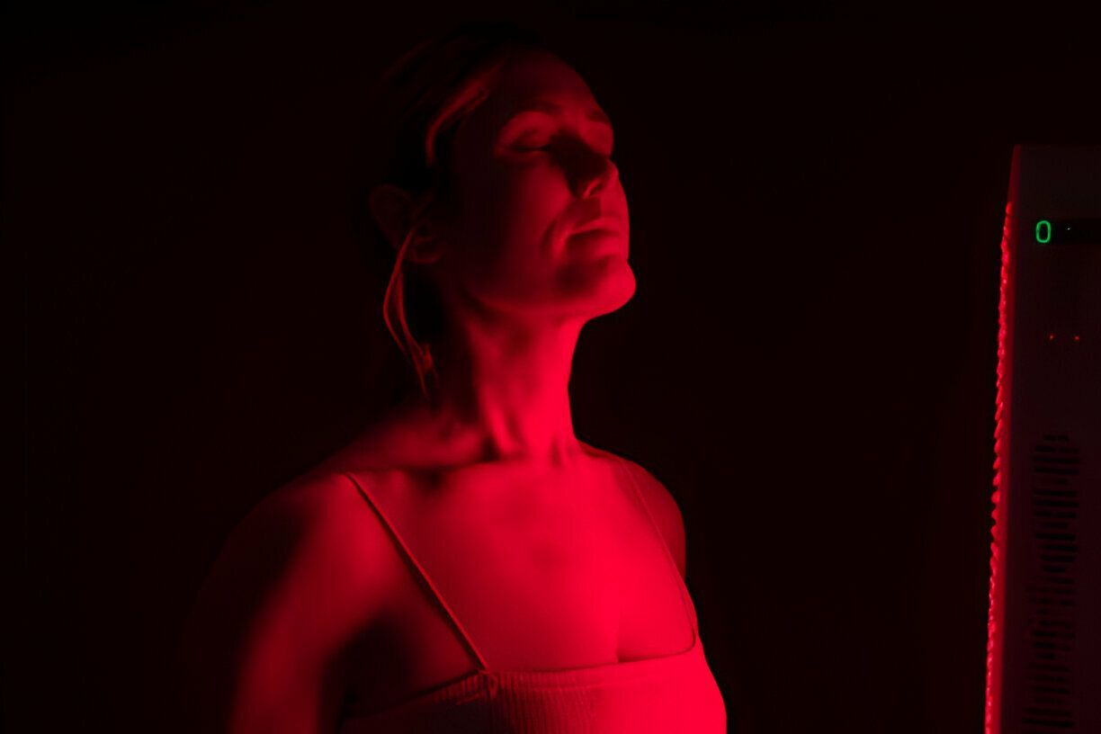 A woman is standing under a red light in a dark room.