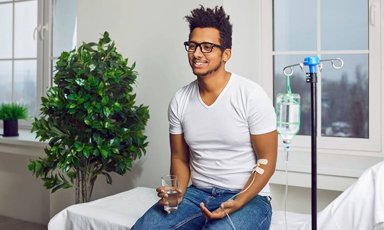 a man is sitting on a hospital bed holding a glass of water