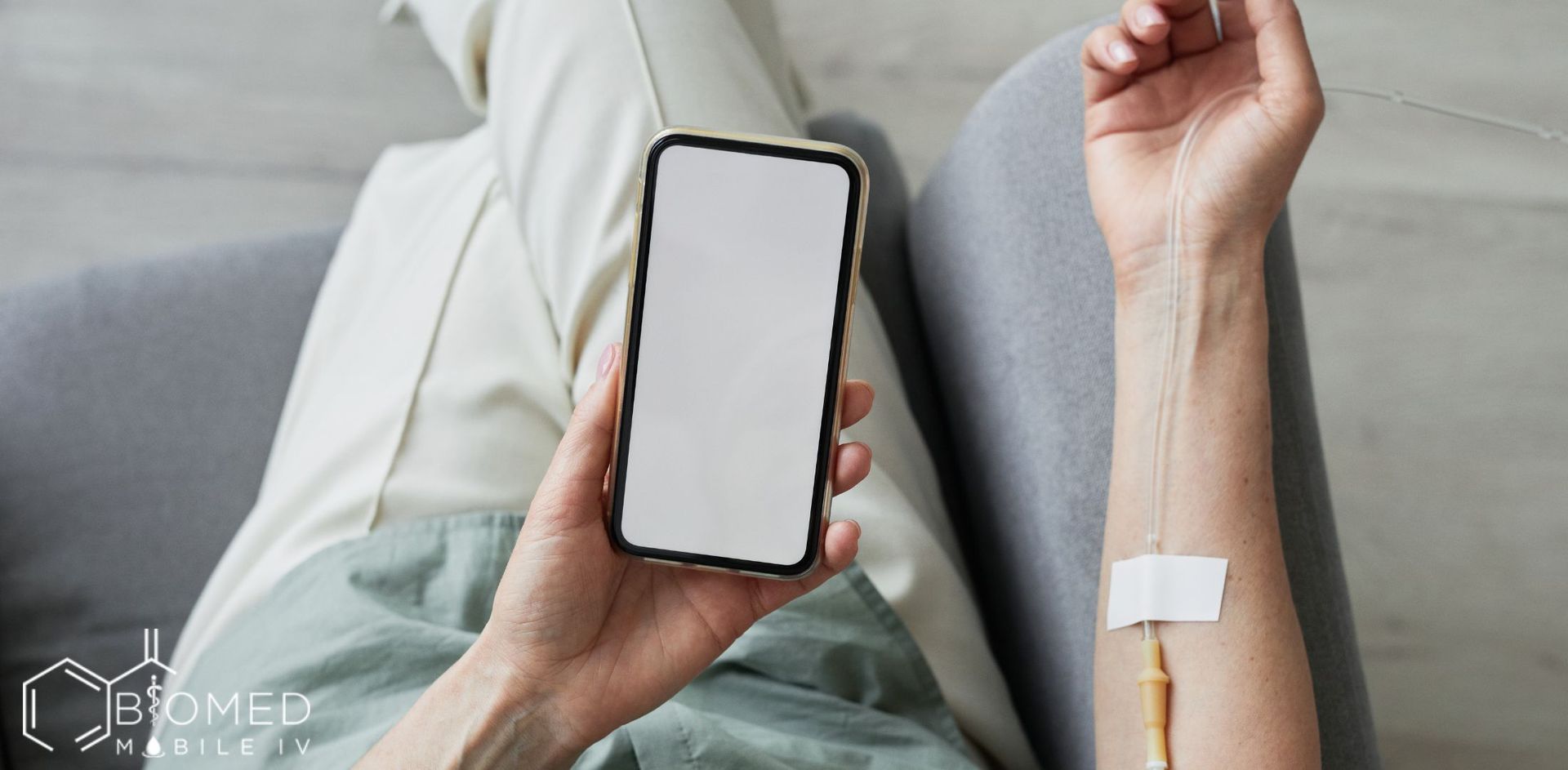 Woman using cellphone while having iv drip