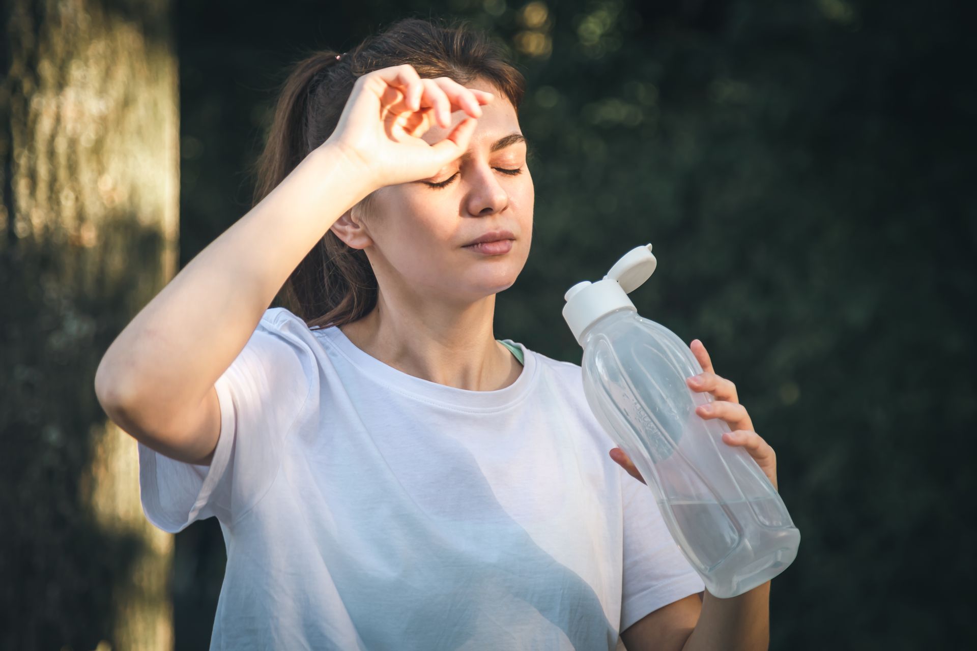 Attractive young woman drinks water after jogging in the park.