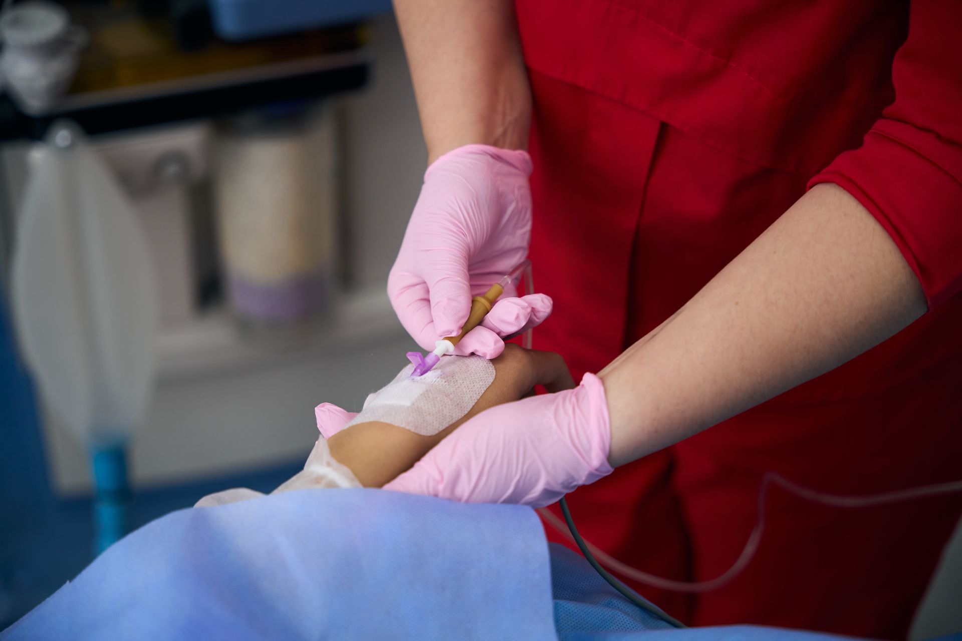 Medic in a red uniform administers an IV to a patient
