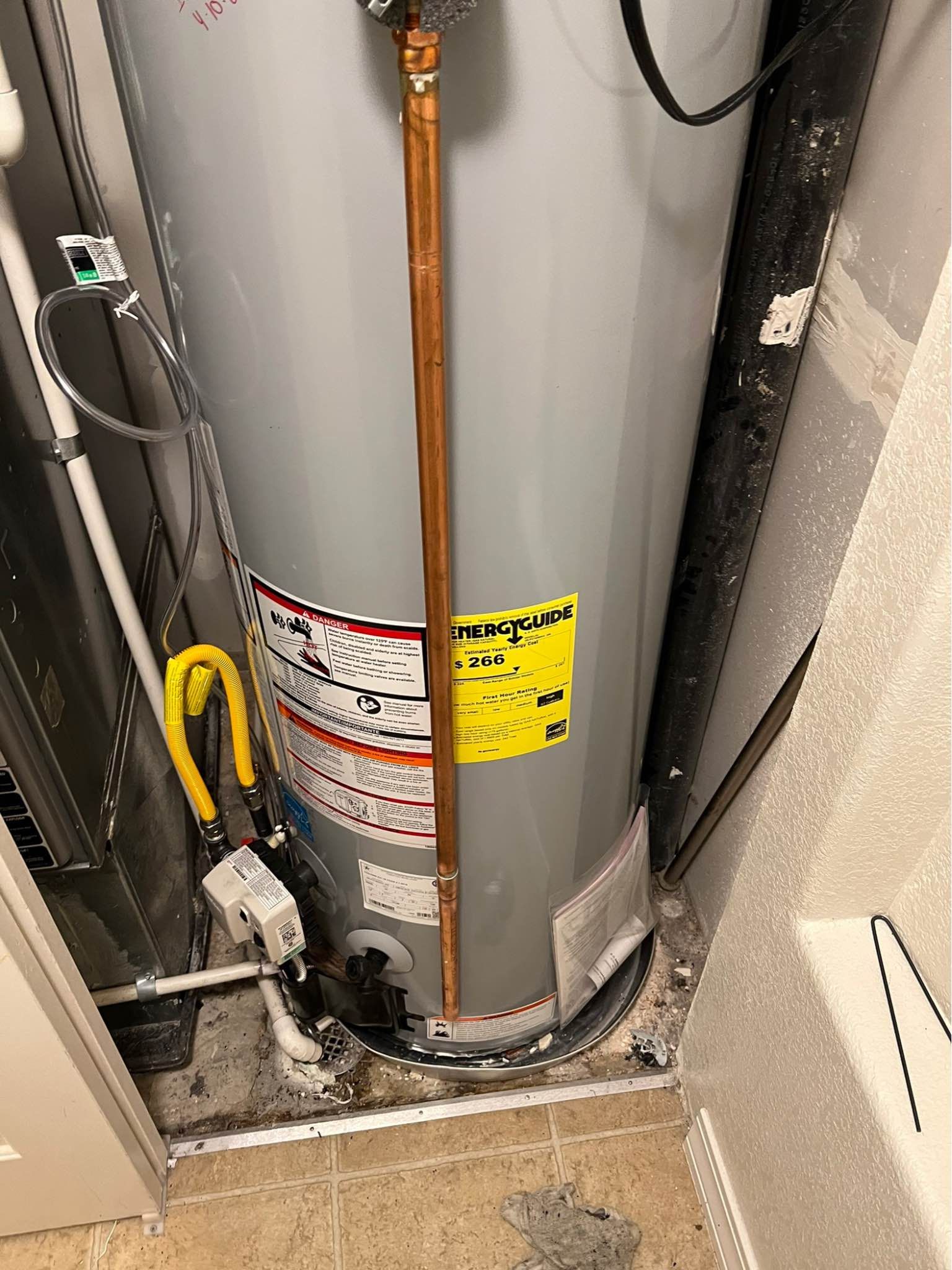 A water heater is sitting in a corner of a room.