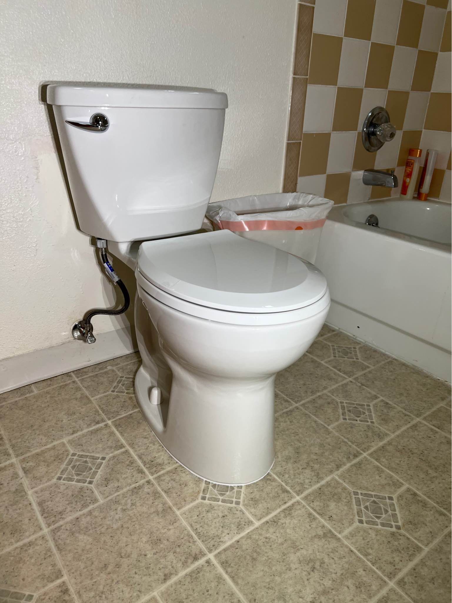 A white toilet is sitting in a bathroom next to a bathtub.