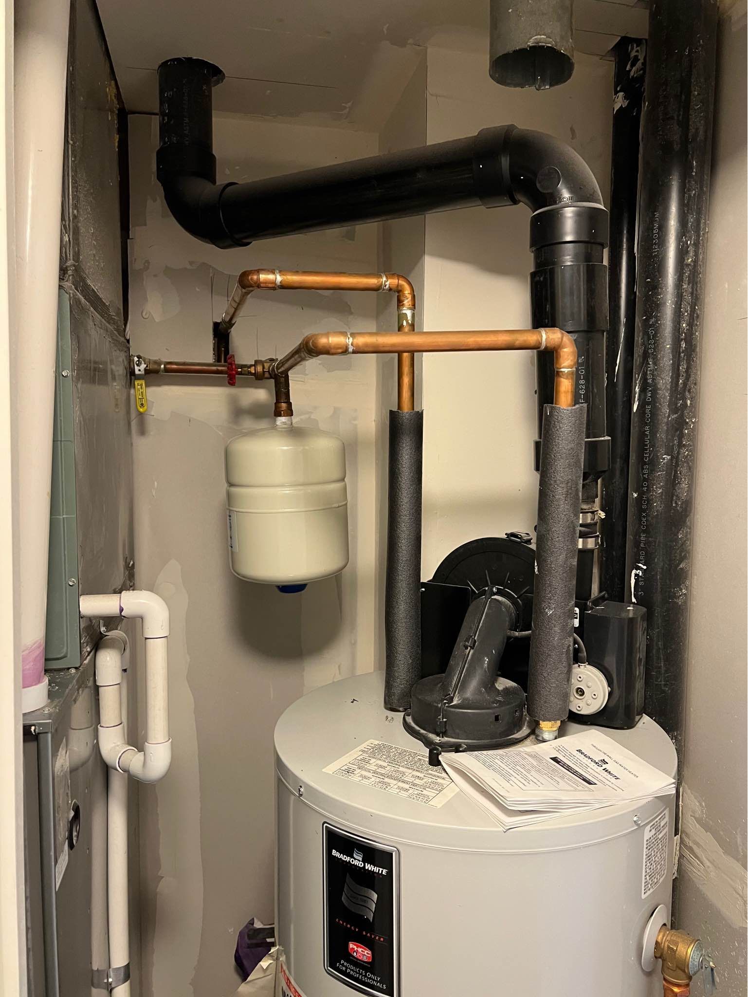 A water heater is sitting in a room next to a pipe.