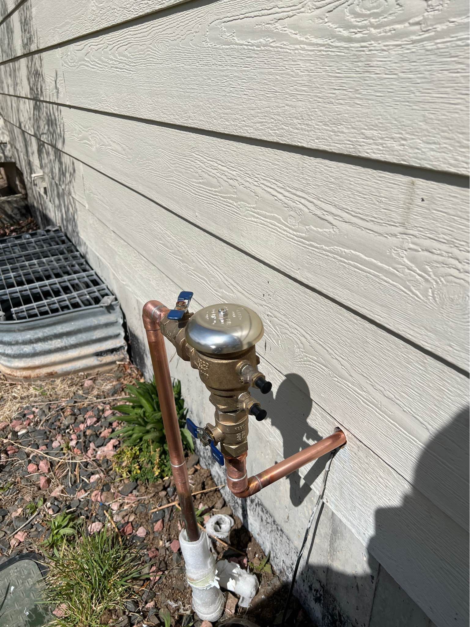 A copper pipe is attached to the side of a house.