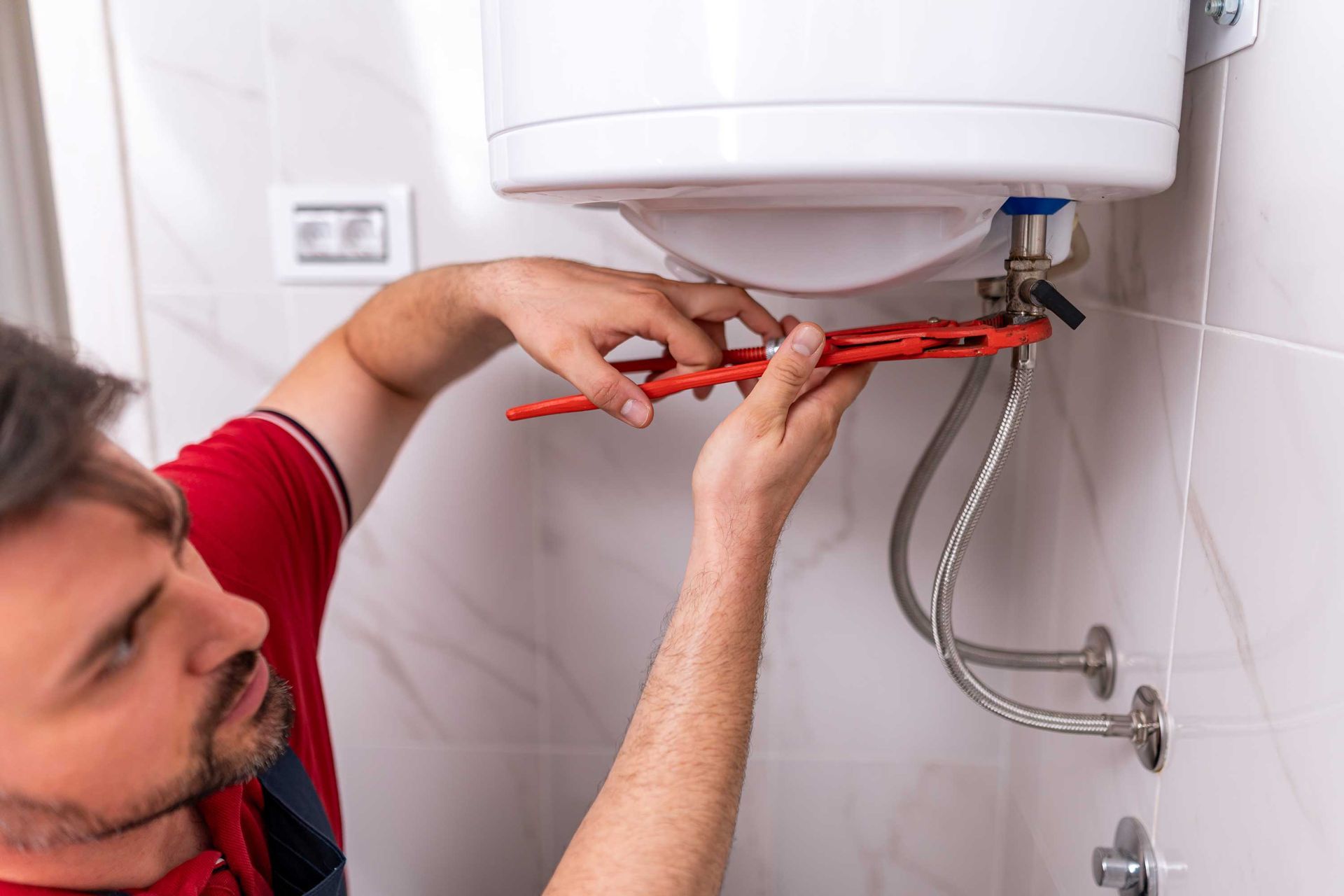 A plumber is performing a hot water system replacement in a modern bathroom.