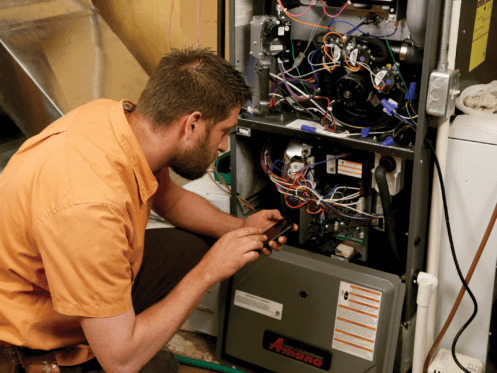 A man is working on an air conditioner with a screwdriver.