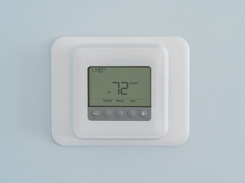 A digital thermostat is mounted on a wall.