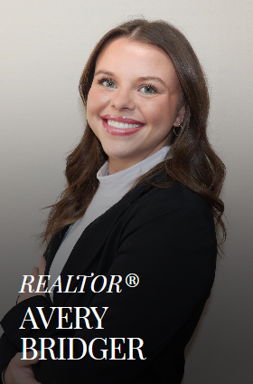 Avery Bridger, smiling, wearing a black blazer and REALTOR® logo.