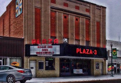 Plaza-3 theater exterior with marquee listing movie titles, Rogue One, Sing, and Underworld. Brick building with snow.