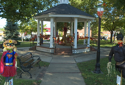 Gazebo decorated for fall with scarecrows in a park setting.