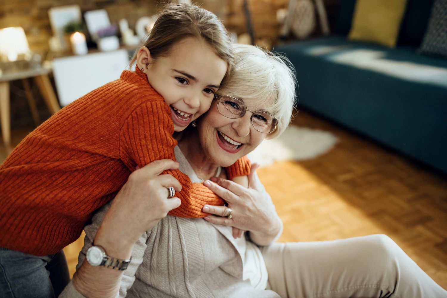 A little girl is hugging an older woman in a living room.