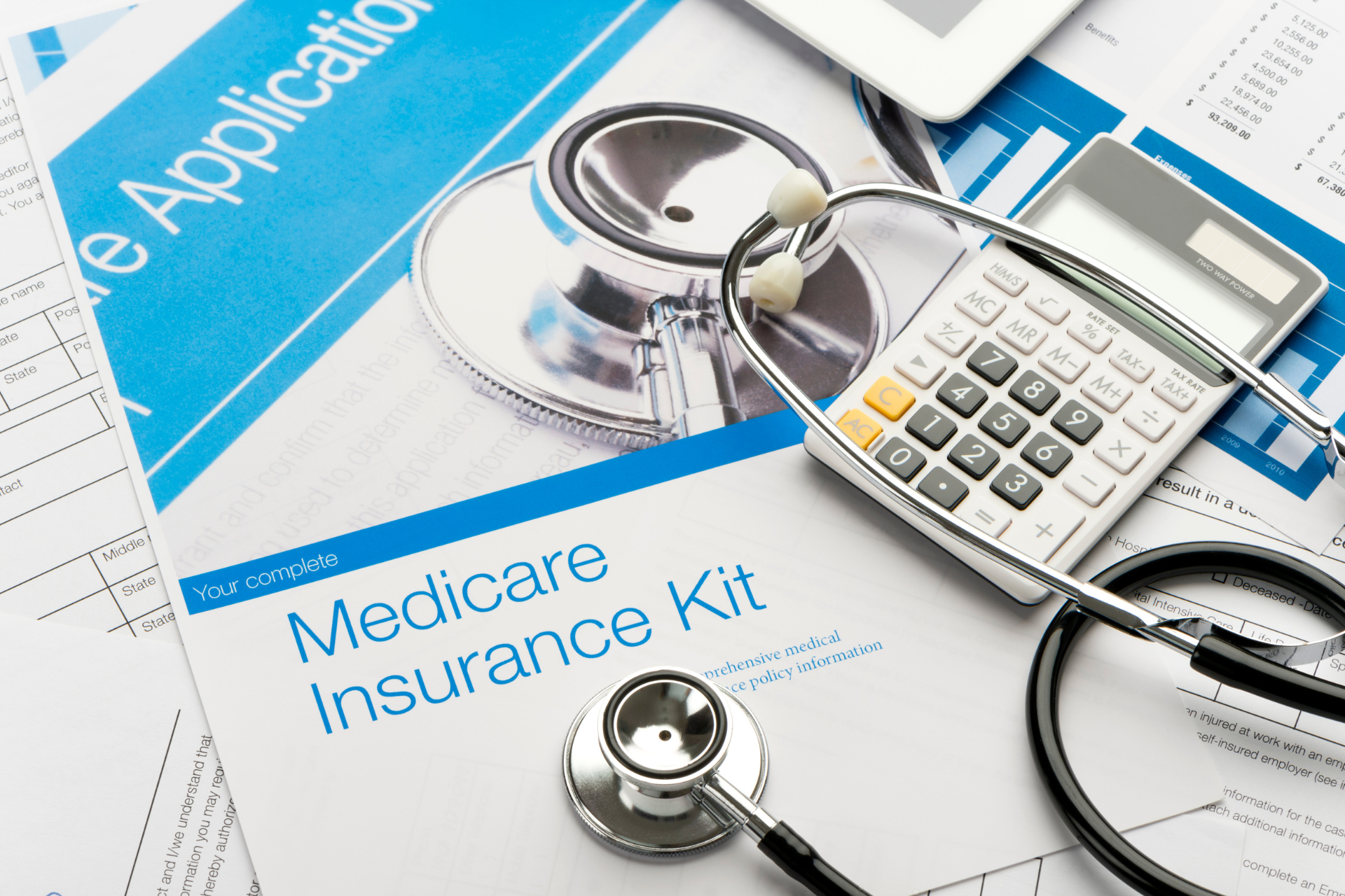 A stethoscope , calculator , and medicare insurance kit are on a table.