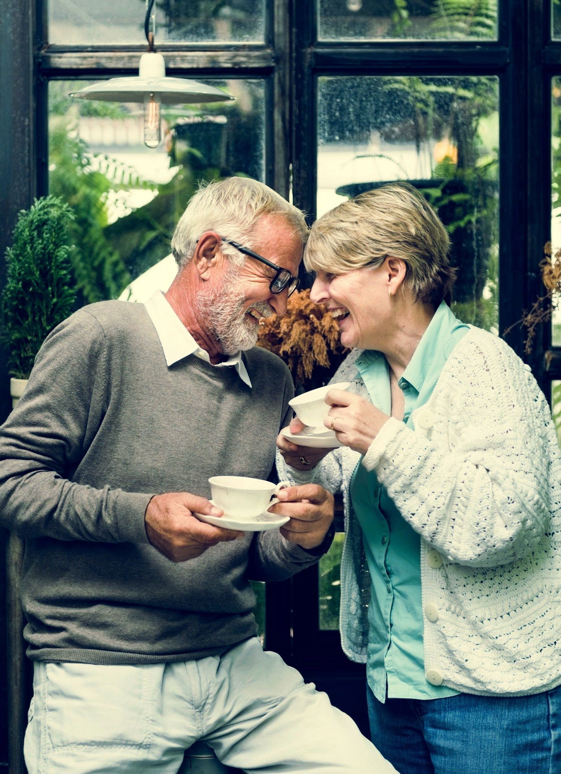 A man and a woman are sitting next to each other drinking coffee.
