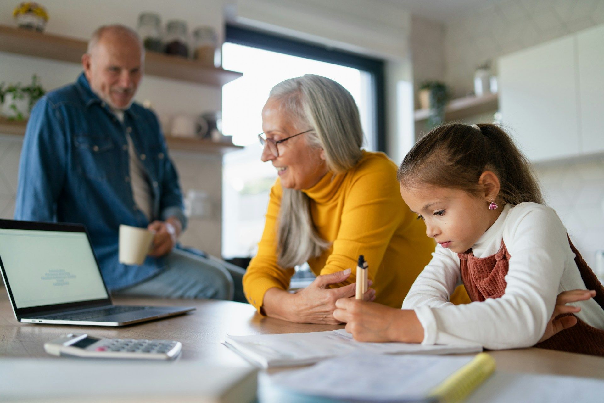 A little girl is sitting at a table with her grandparents.