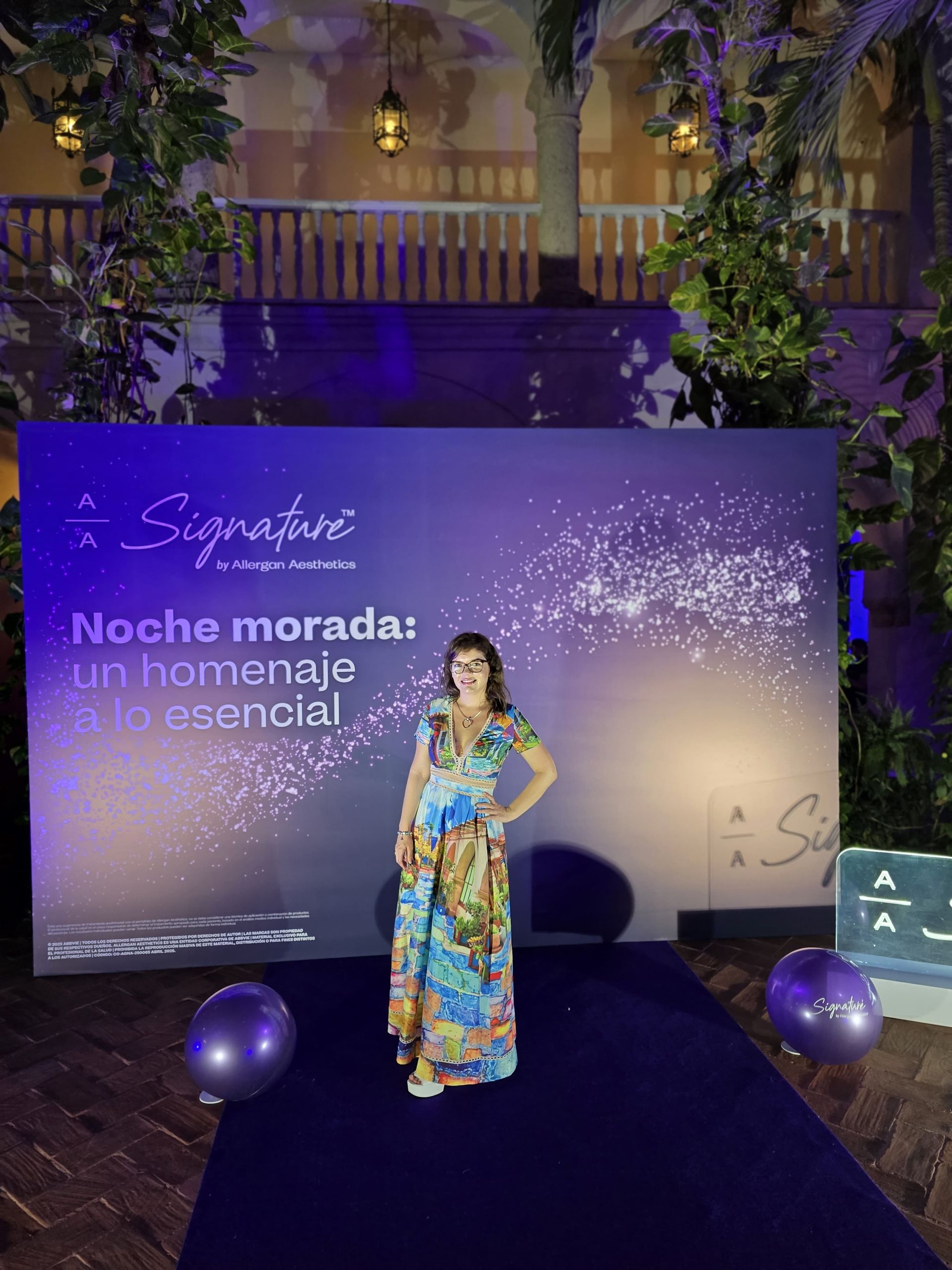 los médicos estéticos debes capacitarse de forma continua A woman in a dress is standing in front of a purple wall.