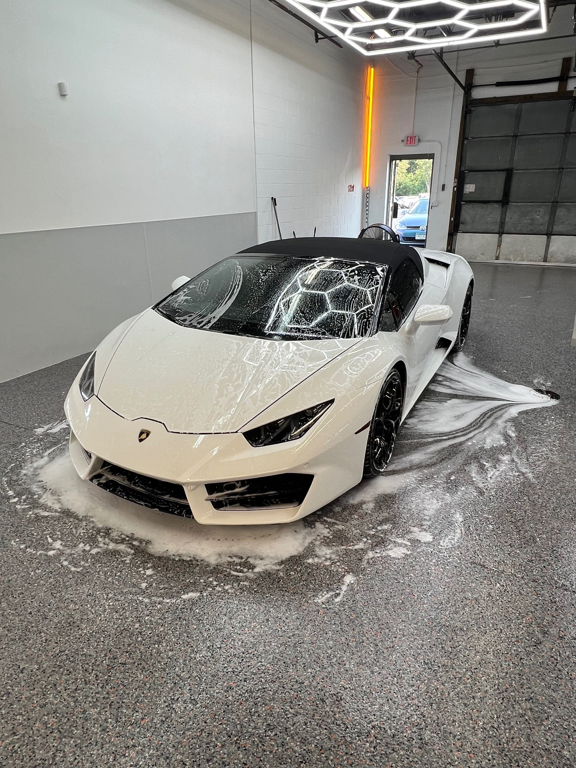 A white lamborghini huracan is sitting in a garage covered in foam.