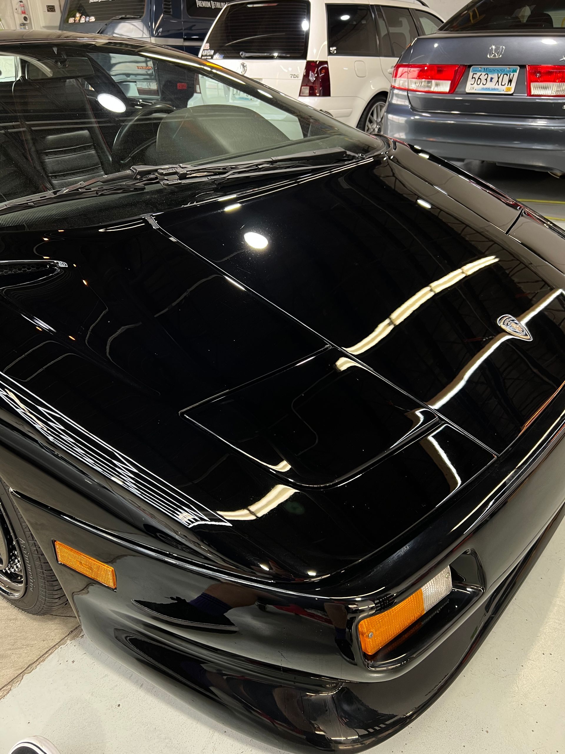 A black car is parked in a garage with other cars