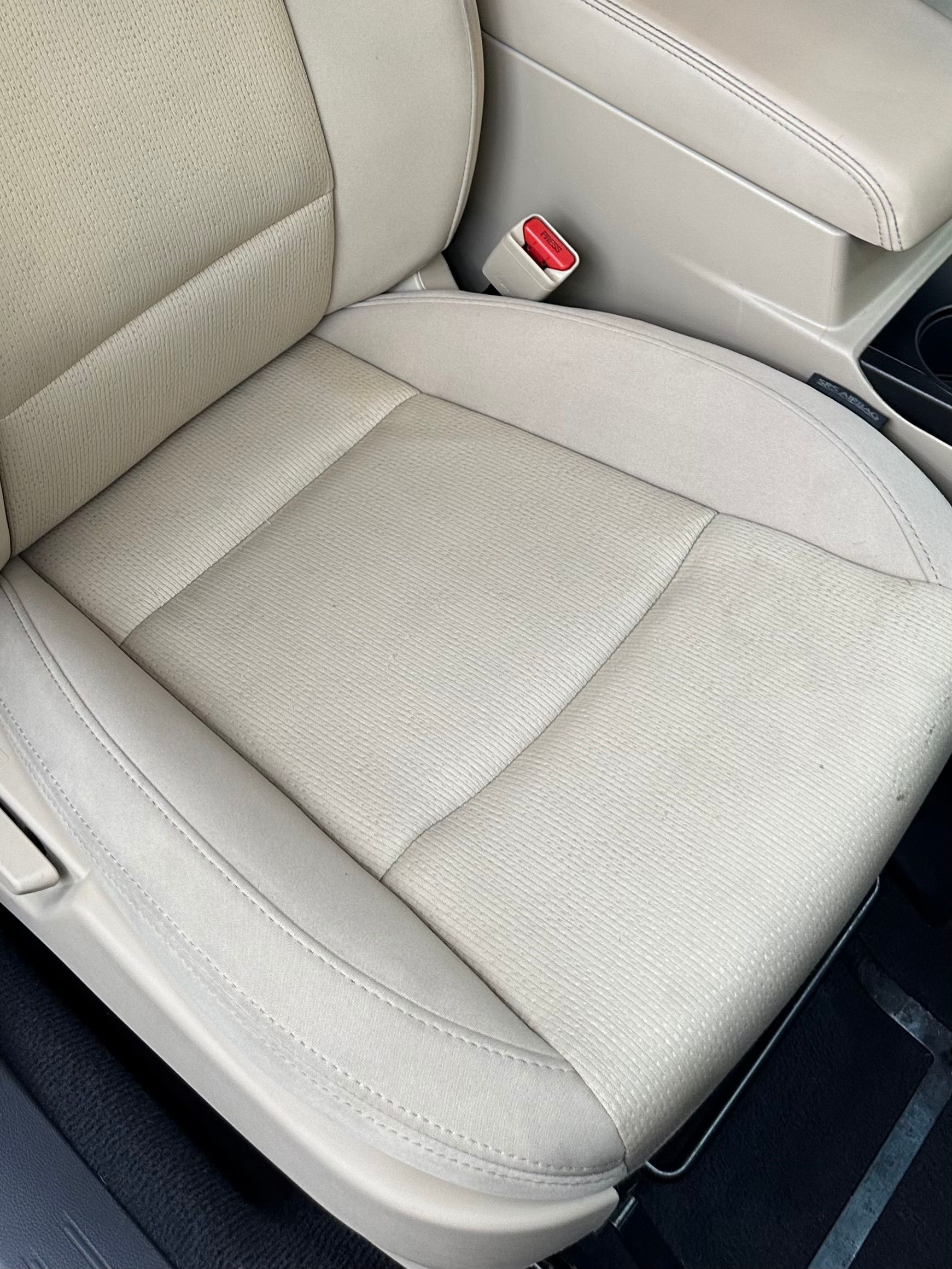 A close up of a car seat with a red seat belt on it.