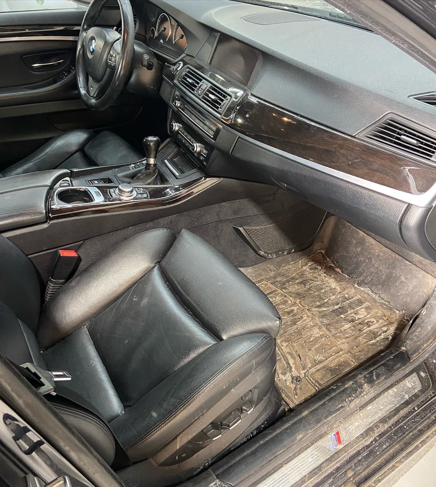 The inside of a car with dirty seats and a dirty floor mat.