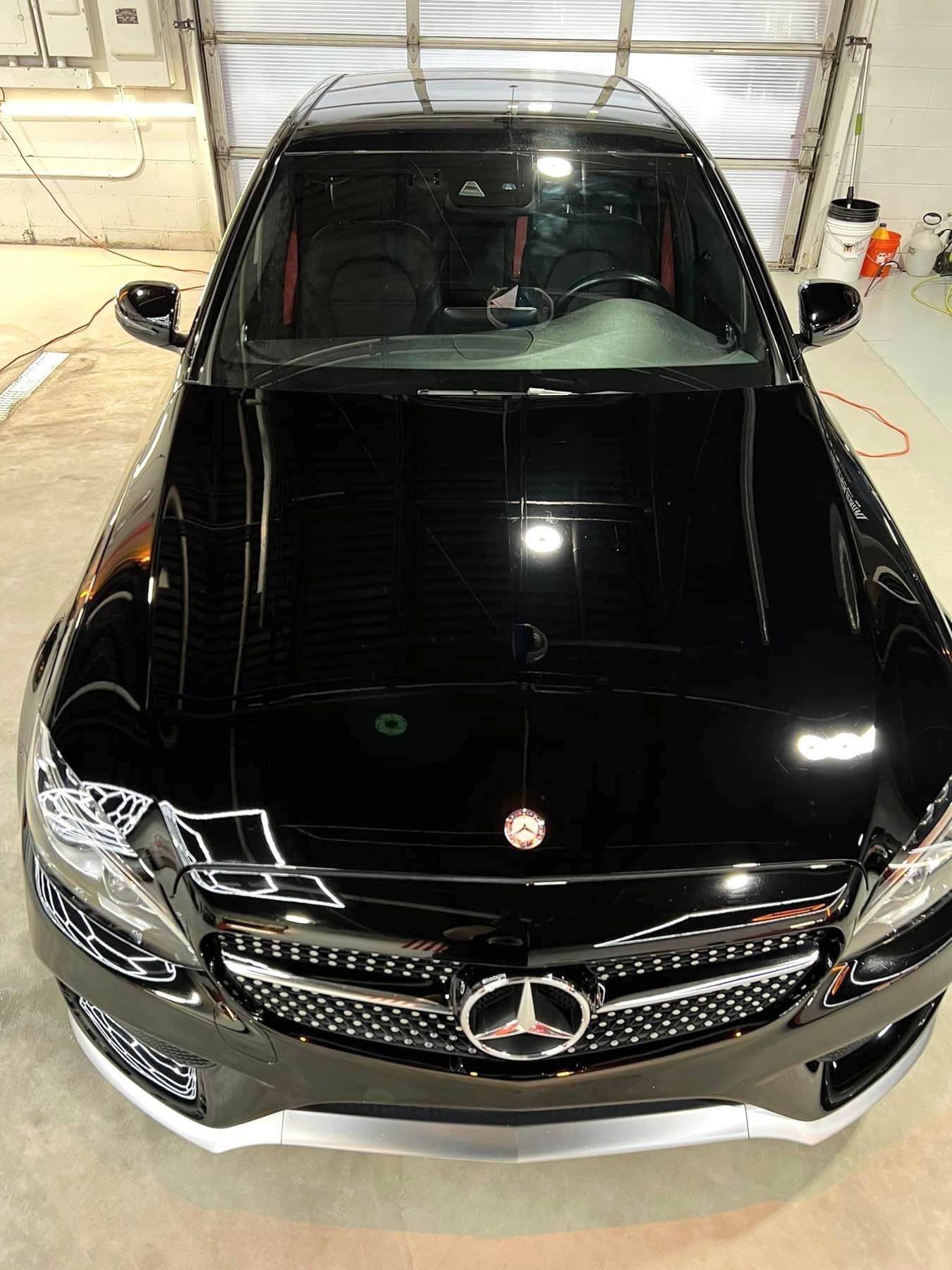 A black mercedes benz is parked in a garage.