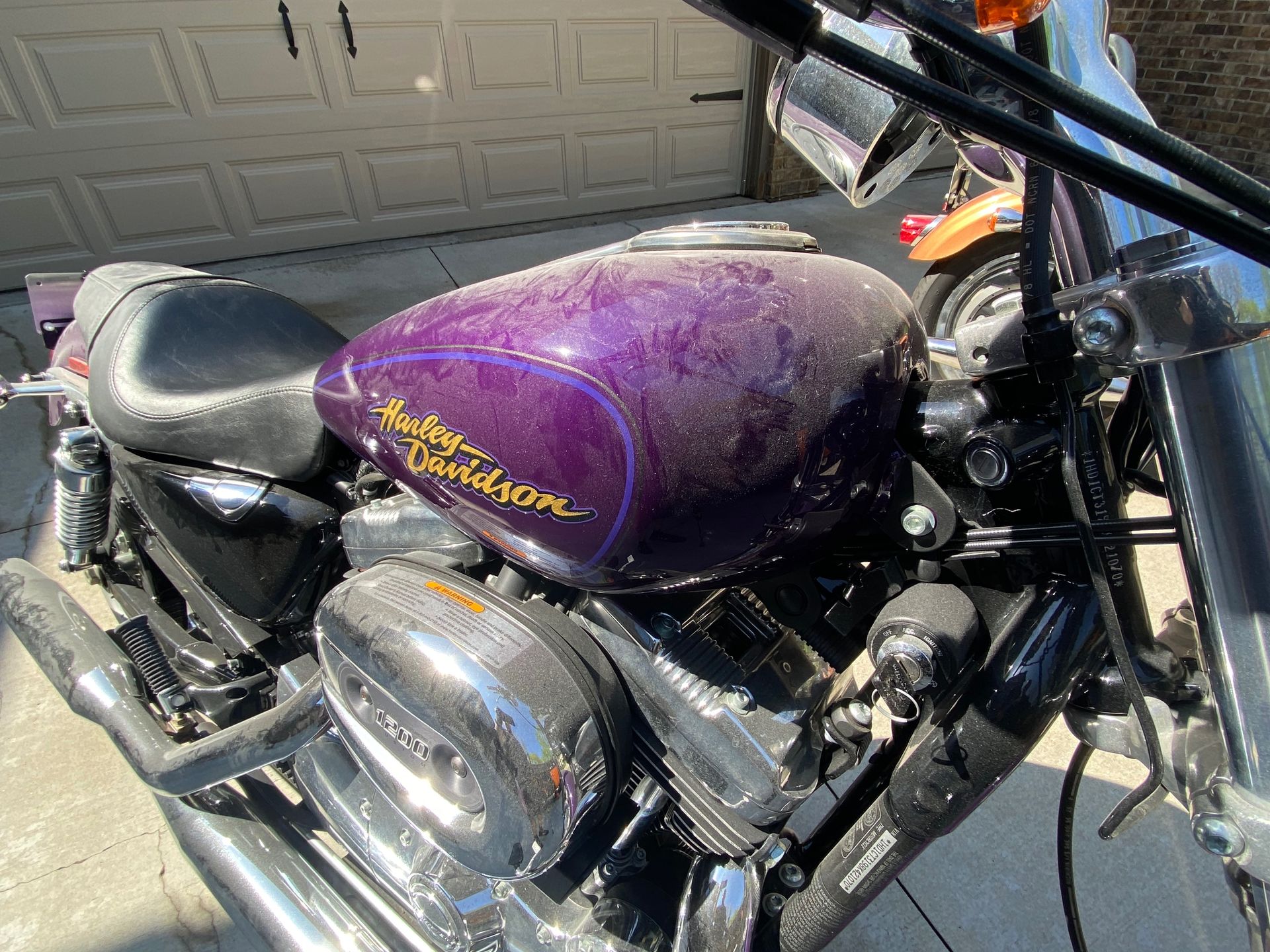 A purple harley davidson motorcycle is parked in front of a garage door.