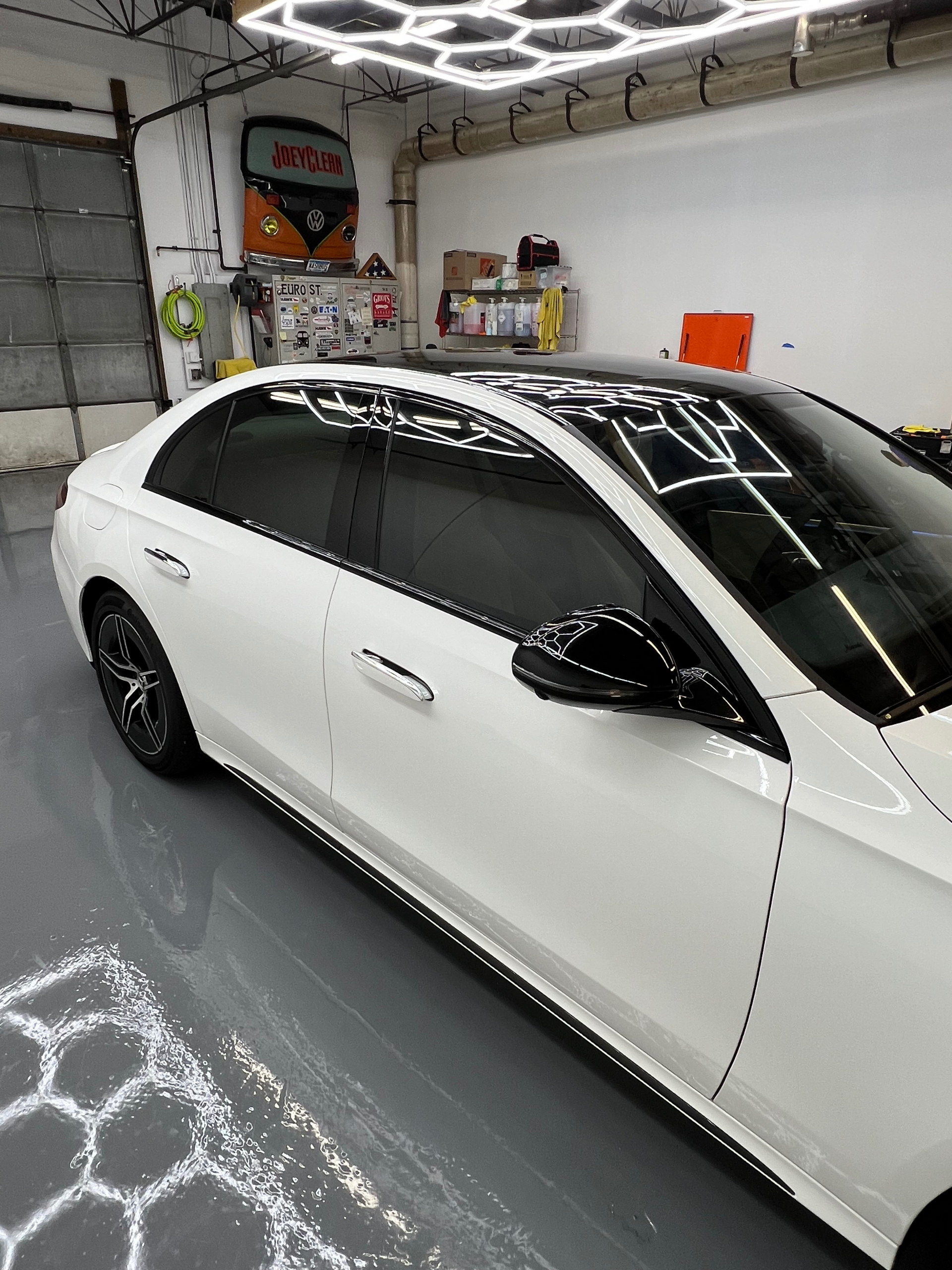 A white car with black windows is parked in a garage.